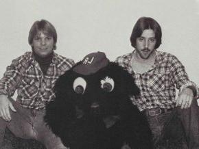 Two people sitting with bear mascot costume