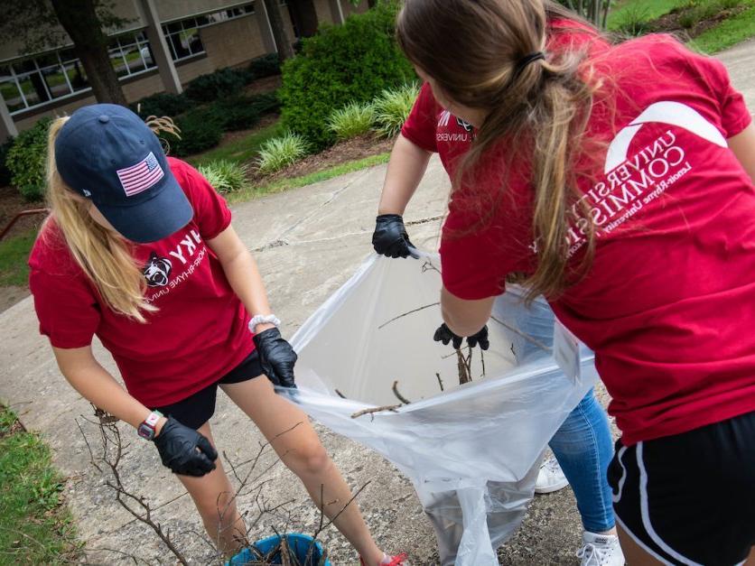 作为社区服务项目的一部分，三名学生志愿者正在清理院子里的垃圾.