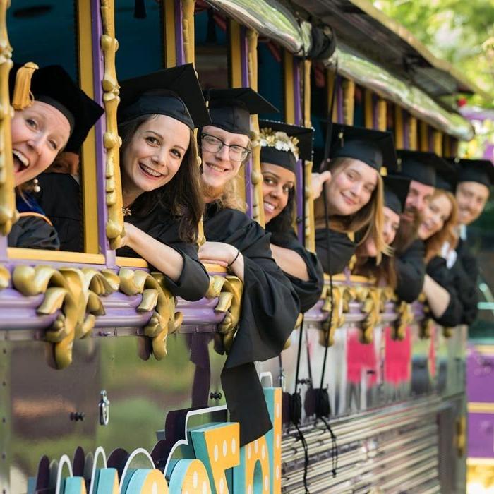Graduate students smiling on trolley on way to commencement ceremony